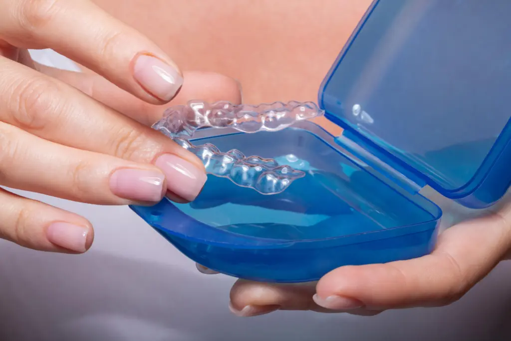 A woman placing her clear retainer into its protective case.
