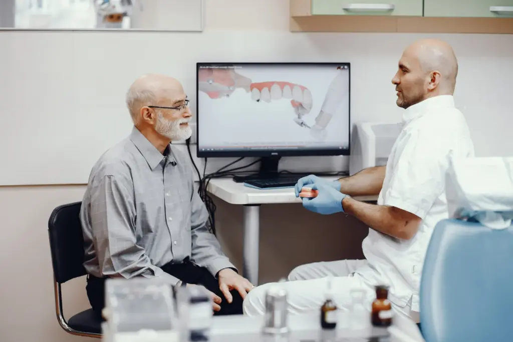 Dentist discussing dental implant options with a patient using a model during a relaxed consultation.